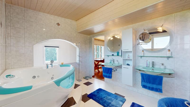 Bathroom with a large bathtub and two sinks, both with mirrors, a wooden cabinet, wooden floor, and wooden ceiling.