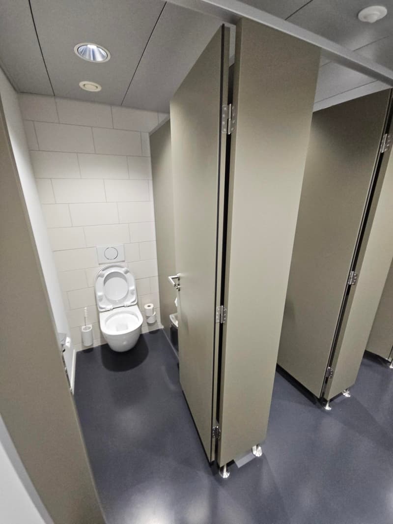an empty bathroom with 2 stall, 1 toilet, and a hand dryer