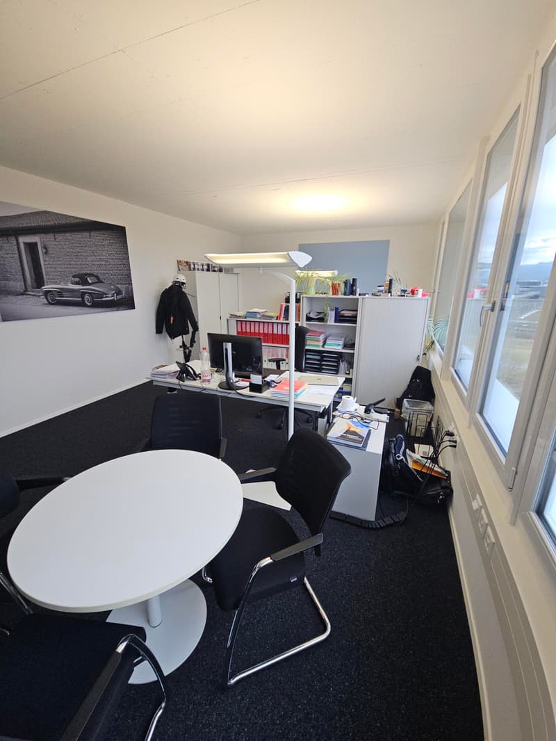 modern office with large windows, desk, chairs, shelves, white flooring, round table