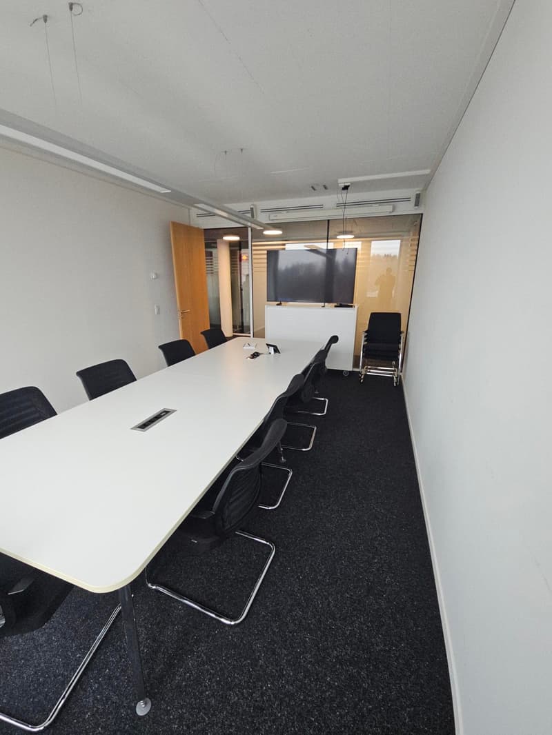 long table with chairs, TV mounted on wall, office entrance