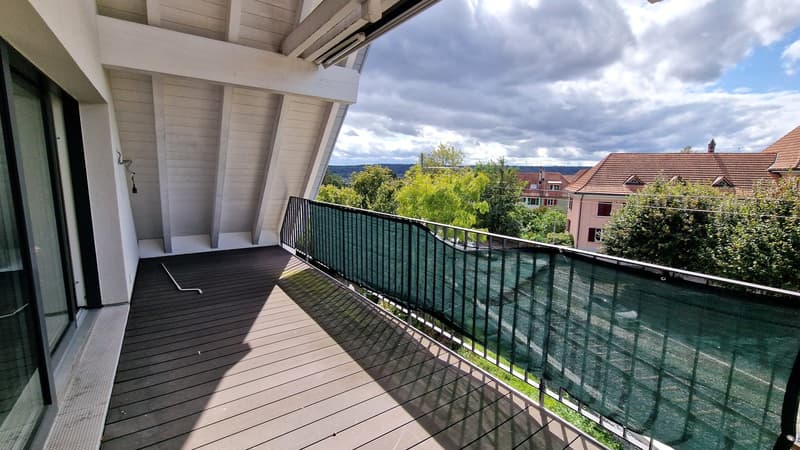 large balcony, wood deck, metal railing, green fabric panel, view of green surroundings