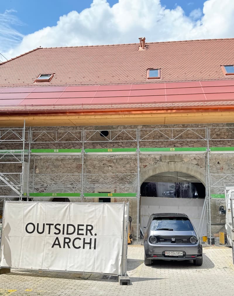 exterior of building under construction, stone walls, red roof, scaffolding, vehicle parked