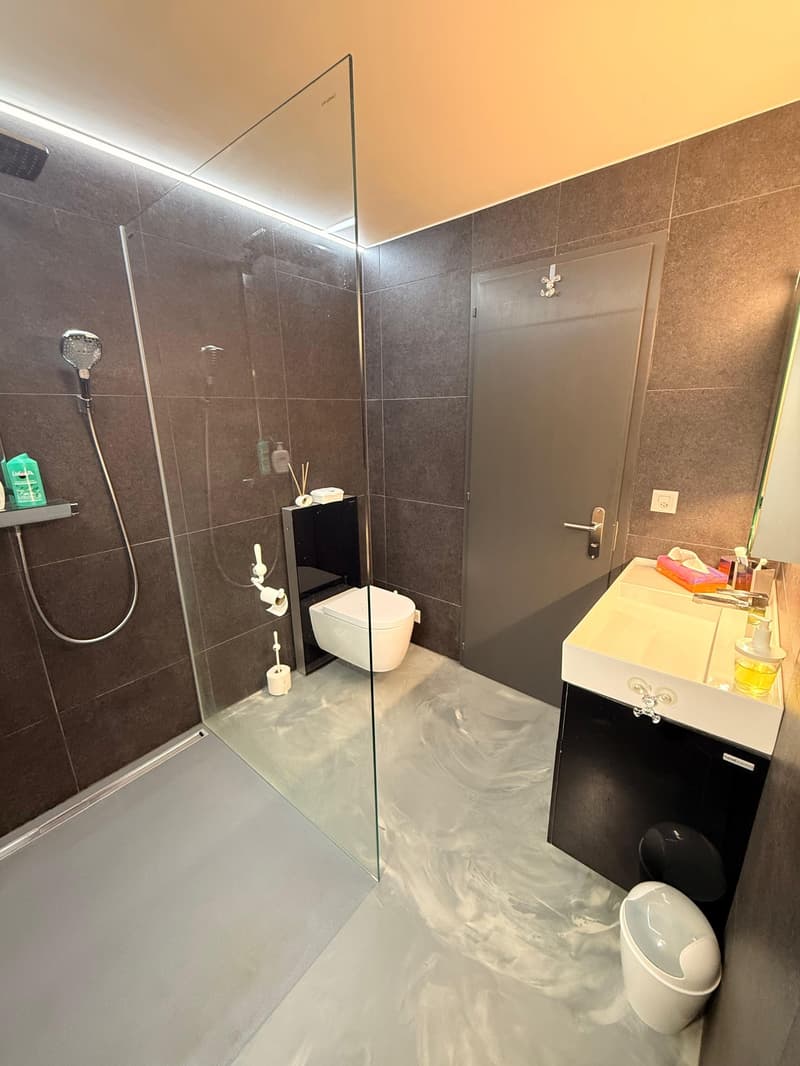 modern bathroom with walk-in shower, toilet, sink, and modern features