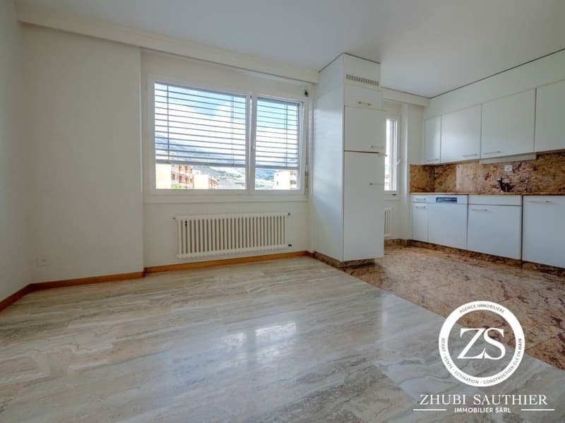 Empty room with white walls, marble floor, window with shutters, built-in white refrigerator and dishwasher