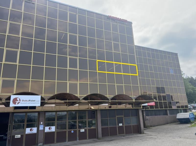 Large office building, glass windows, multiple stories, awnings over entrance, yellow highlighted window, DaKaPaint signage