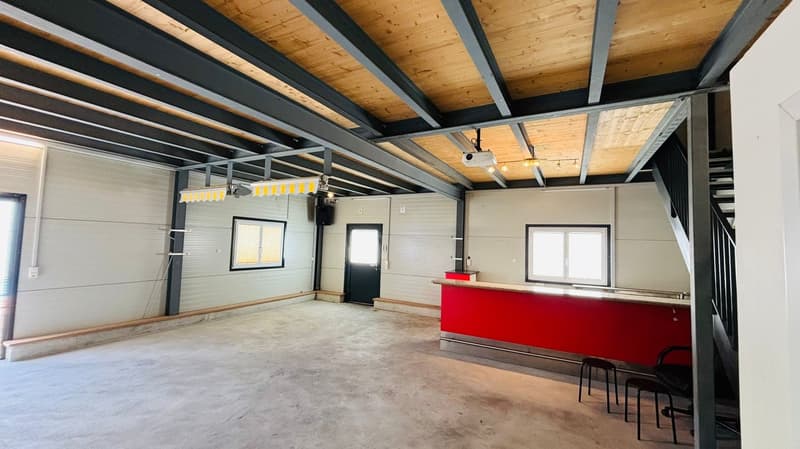 spacious room, metal beams, wooden ceiling, red countertop, black chairs, projector, stairs, windows
