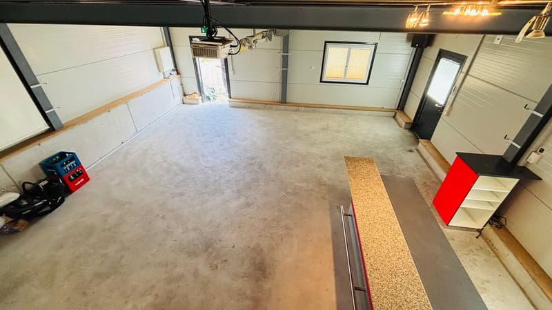 Empty garage with white and grey walls, a grey floor, cabinets, and a door.