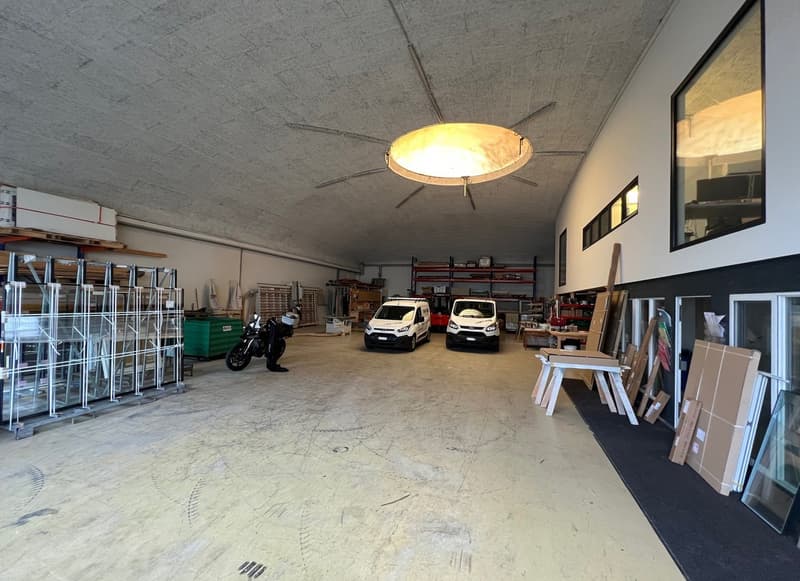 Warehouse space, large open space, concrete floor, 2 vans parked, motorcycle, large windows, shelves with boxes