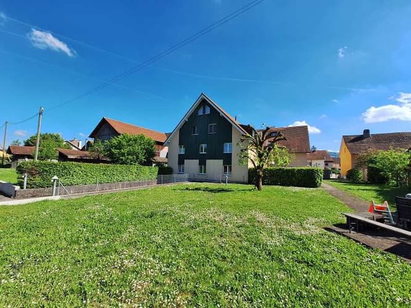 sprawling green grass, hedges, trees, residential buildings in the background