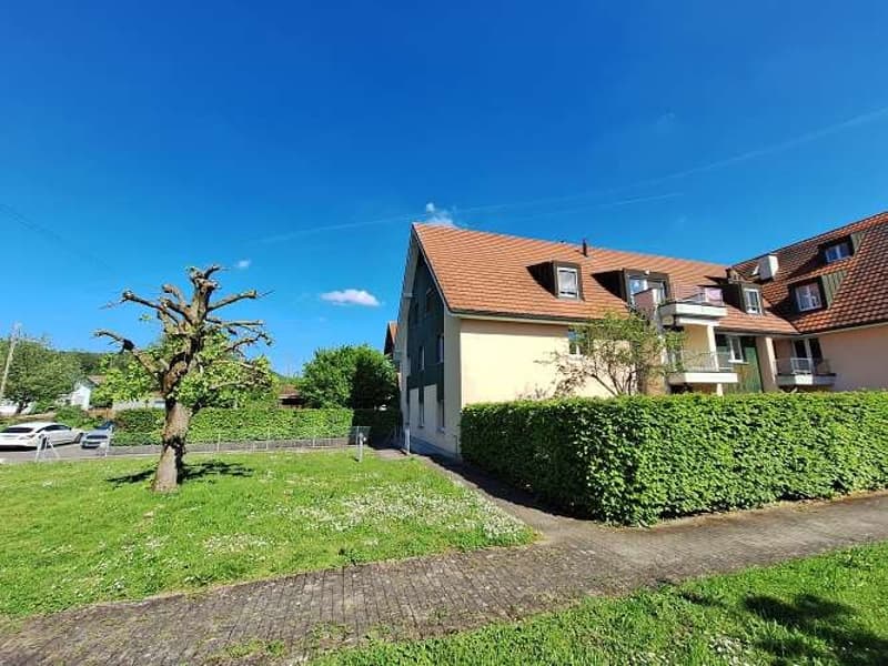 2 story house, brown roof, beige wall, balcony, driveway, car parked, green lawn, hedge