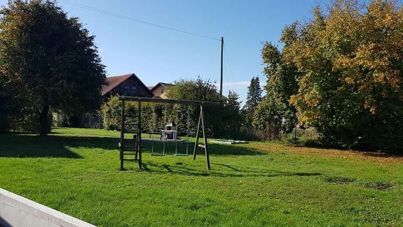 Lawn, swing set, house in background, trees
