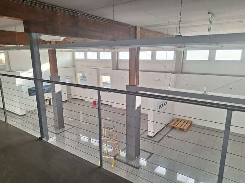 Large open space, metal railings, exposed wooden beams, grey tiles, under construction