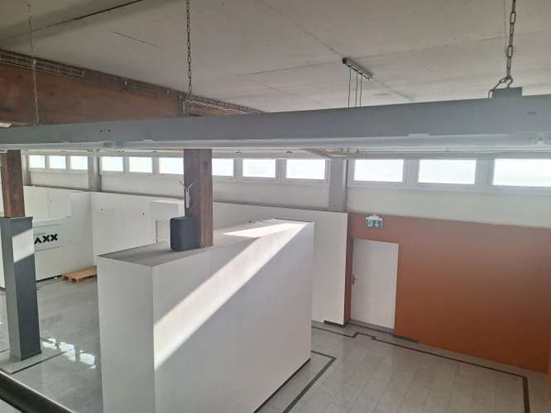 Empty office with white tiles, wooden beam, large windows, two pillars