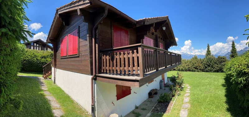 Wooden chalet with red shutters, wooden balcony, concrete basement