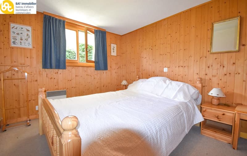 a bedroom with wooden walls, bed, nightstands, lamps, and picture frames