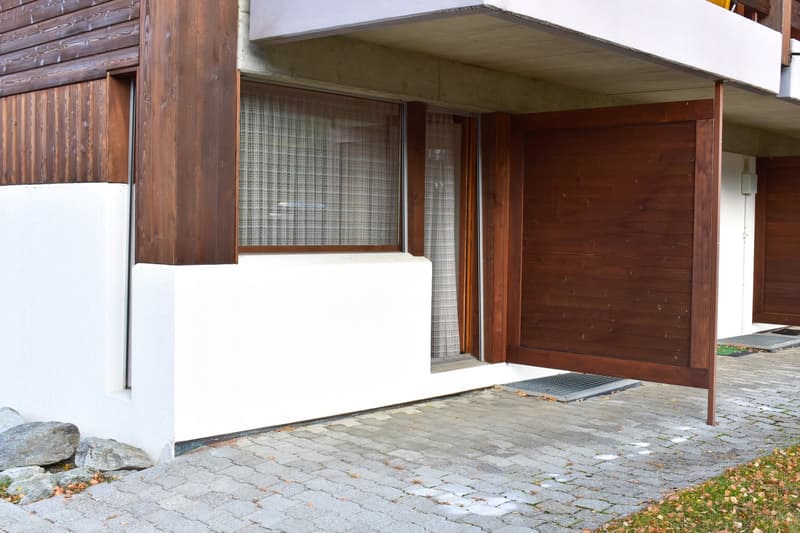 2-story wooden house with a garage, white walls, and a covered entrance area with a paved walkway.
