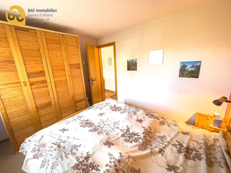 Wooden wardrobe, white walls, patterned bedding, artwork on the walls