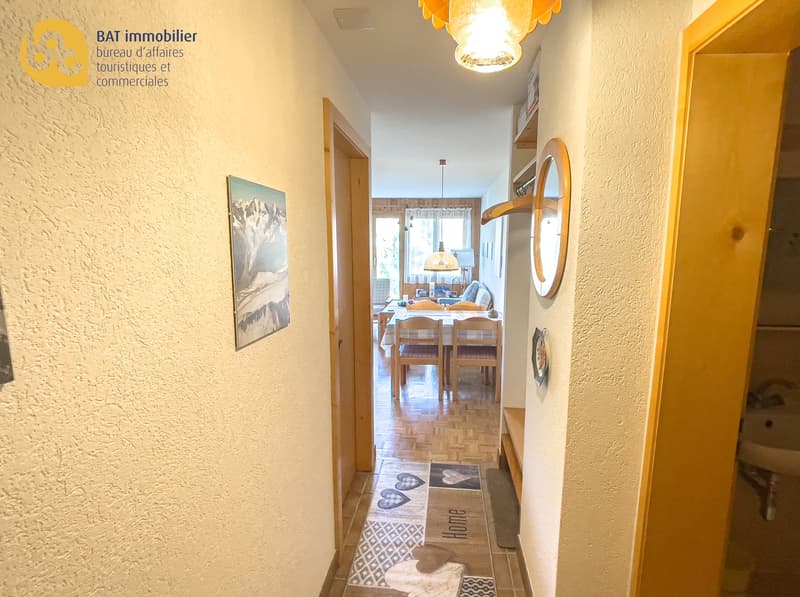 Hallway leading to a dining room, hardwood floors, artwork on the wall, decorative lighting fixture