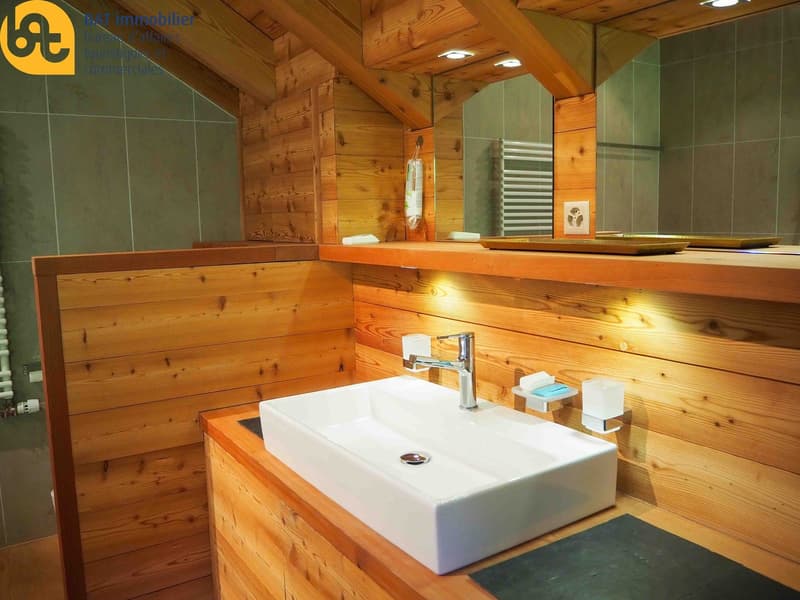 Rustic bathroom with wooden walls and ceiling, white vessel sink, chrome faucet, and green tile walls