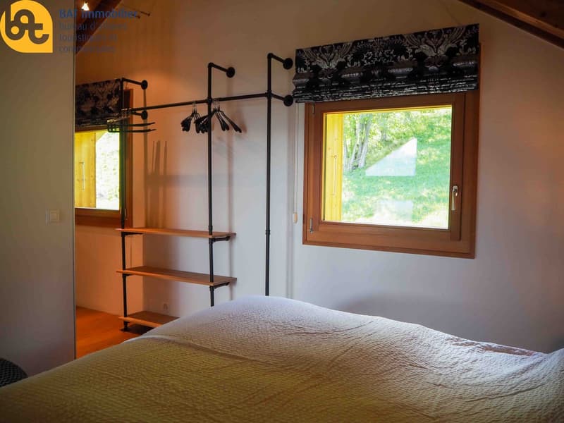 Bedroom with wooden window frame, shelving unit, and clothing rack