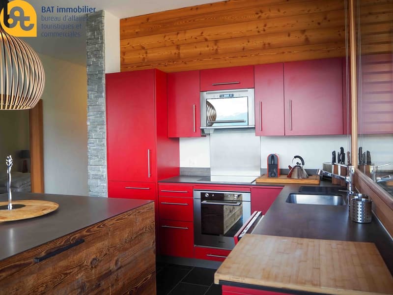 Modern kitchen with red cabinets, wooden countertops, built-in oven, and dishwasher