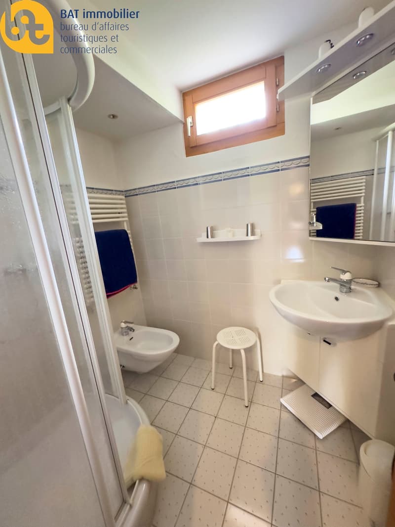 Tiled floor, white walls, sink, toilet, shower stall, towel rack