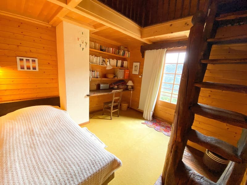 A bedroom with a wooden bed, wooden wardrobe, wooden floor, wooden ladder, and a wooden desk with a chair