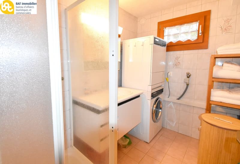 Bathroom with tiled walls, washing machine, dishwasher, and storage cabinet