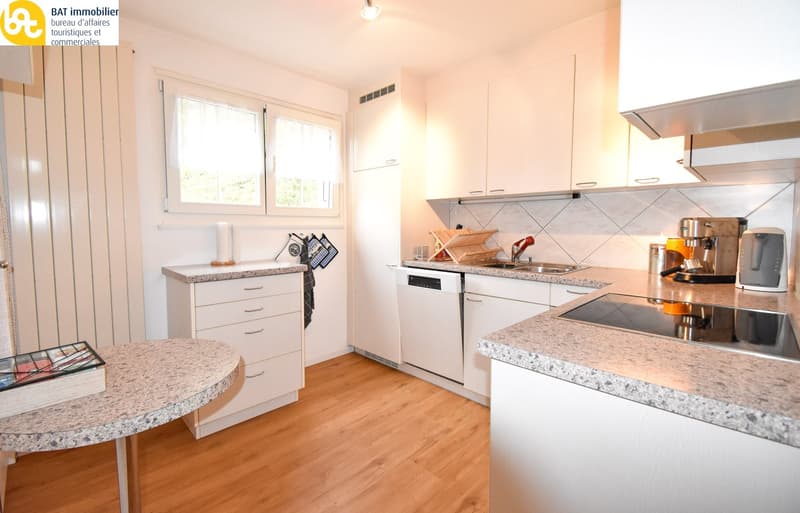 Spacious kitchen with white cabinets, granite countertops, stainless steel appliances including a dishwasher, and a small dining area with a round table.