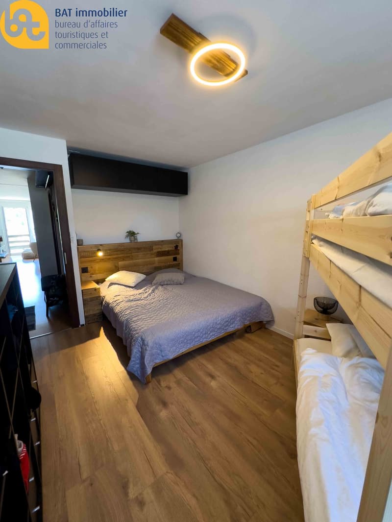 Bedroom with wooden headboard, bunk beds, hardwood flooring, and a circular ceiling light fixture.