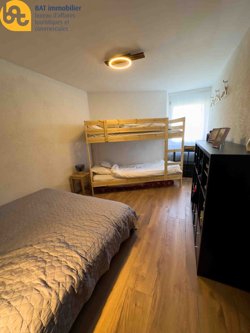 Bedroom with wooden bunk bed, wooden floor, and dark dresser