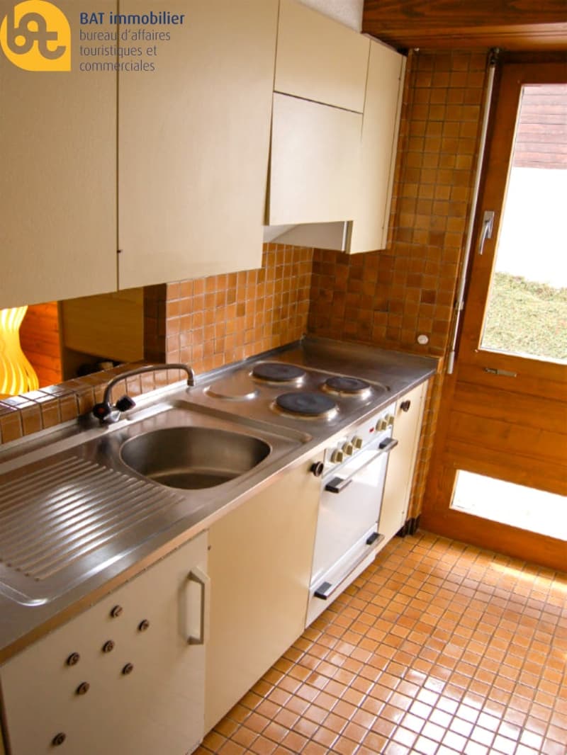 Tiled kitchen with stainless steel sink and stove, wooden cabinets, and a dishwasher