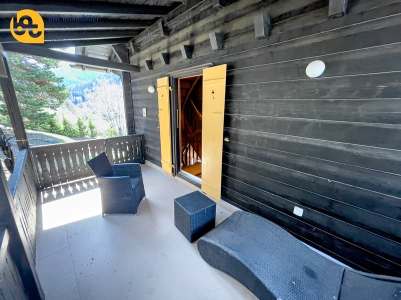 Wooden cabin with a balcony, wooden walls, and large windows overlooking a forested area