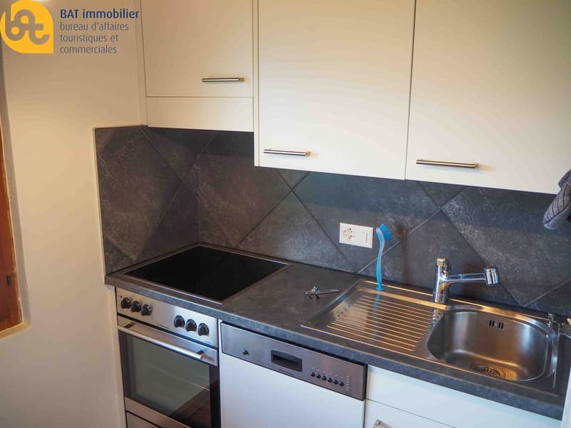Modern kitchen with white cabinets, black stone countertop, built-in electric stove, sink, and dishwasher