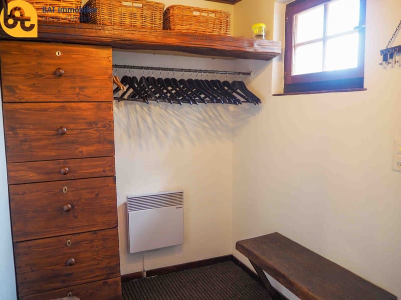 Wooden dresser, hanging rod with clothes hangers, wall heater, wooden bench
