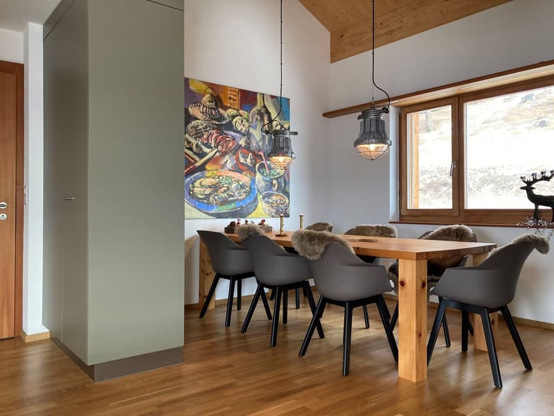 Wooden dining table with 6 chairs, wooden floor, large windows with view of the outdoors, wooden cabinet, art painting