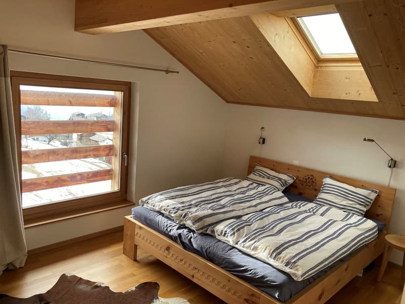 large wooden bed with two beds, wooden wall, window with balcony, wooden floor, wooden ceiling, skylight
