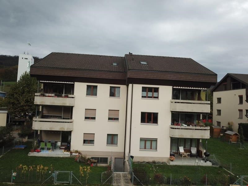 3-story apartment building with white exterior, brown tiled roof, and multiple balconies on each floor.