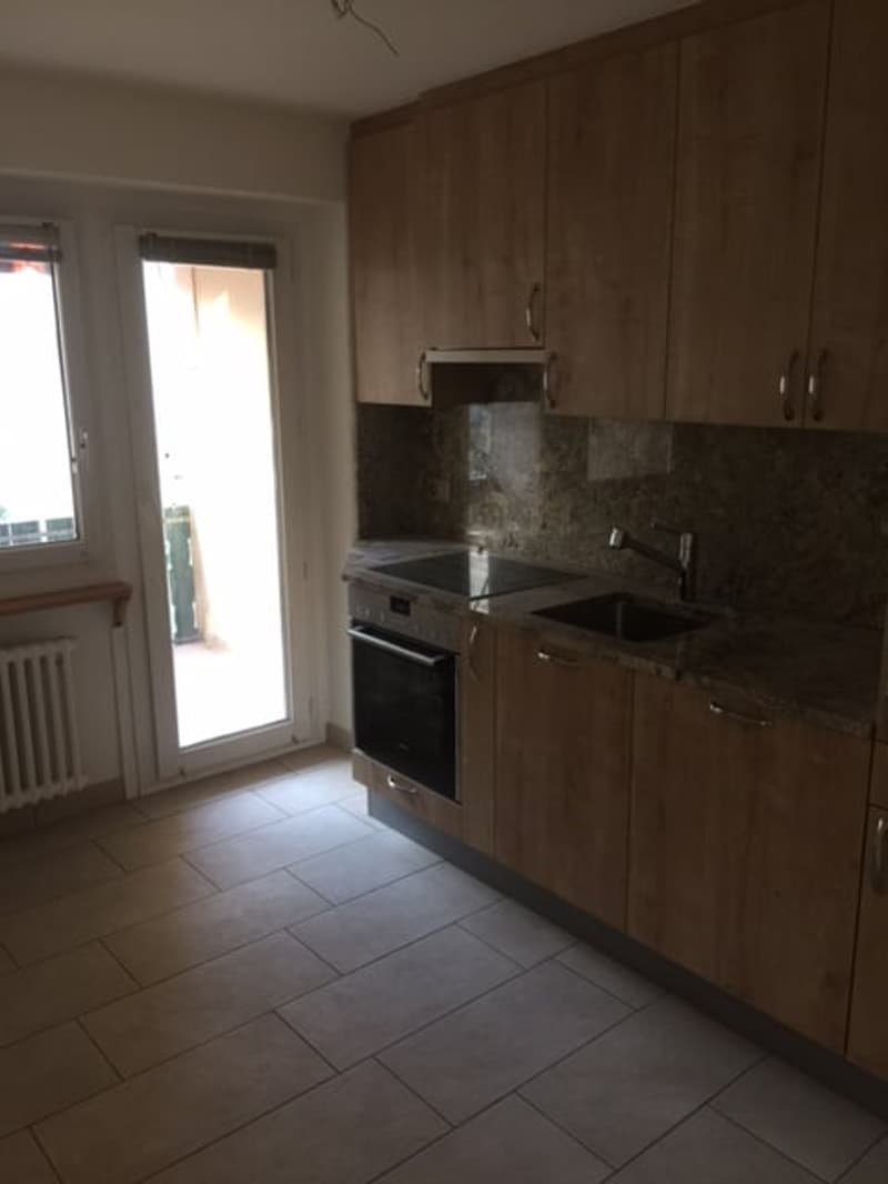 kitchen with wooden cabinets, tiled floor, granite countertop, sink, oven, stove, sliding glass door