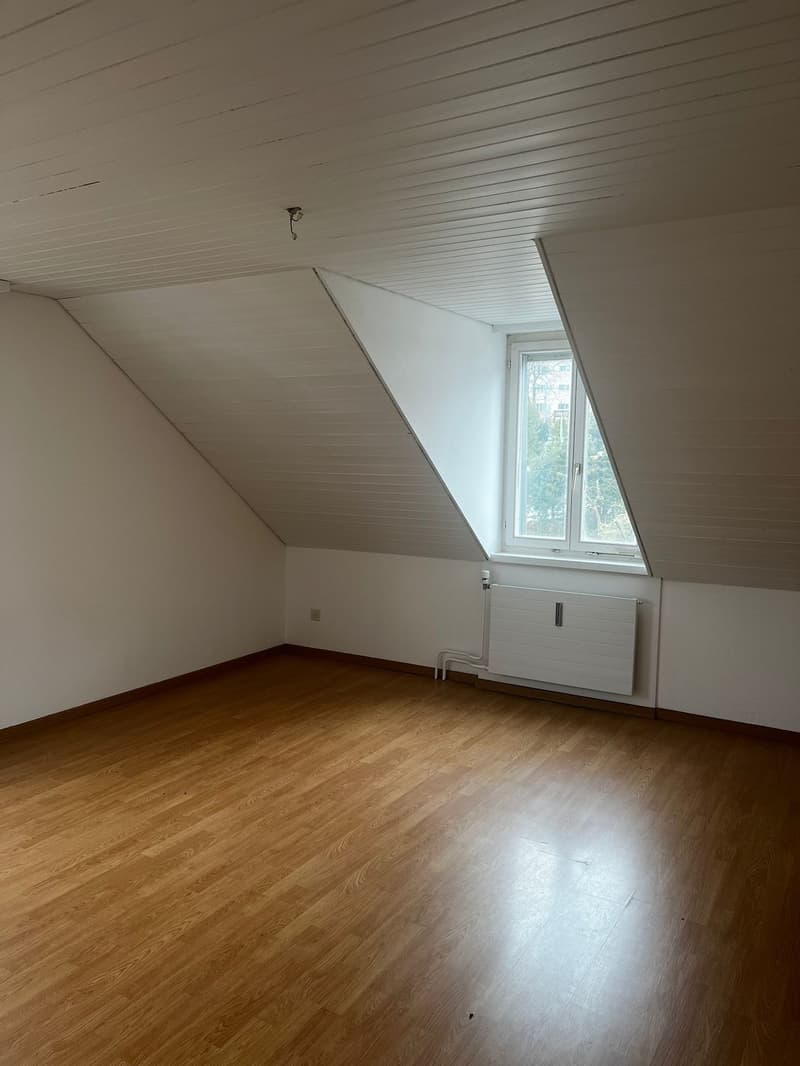 empty room, wooden floor, white walls, slanted ceiling, window, radiator
