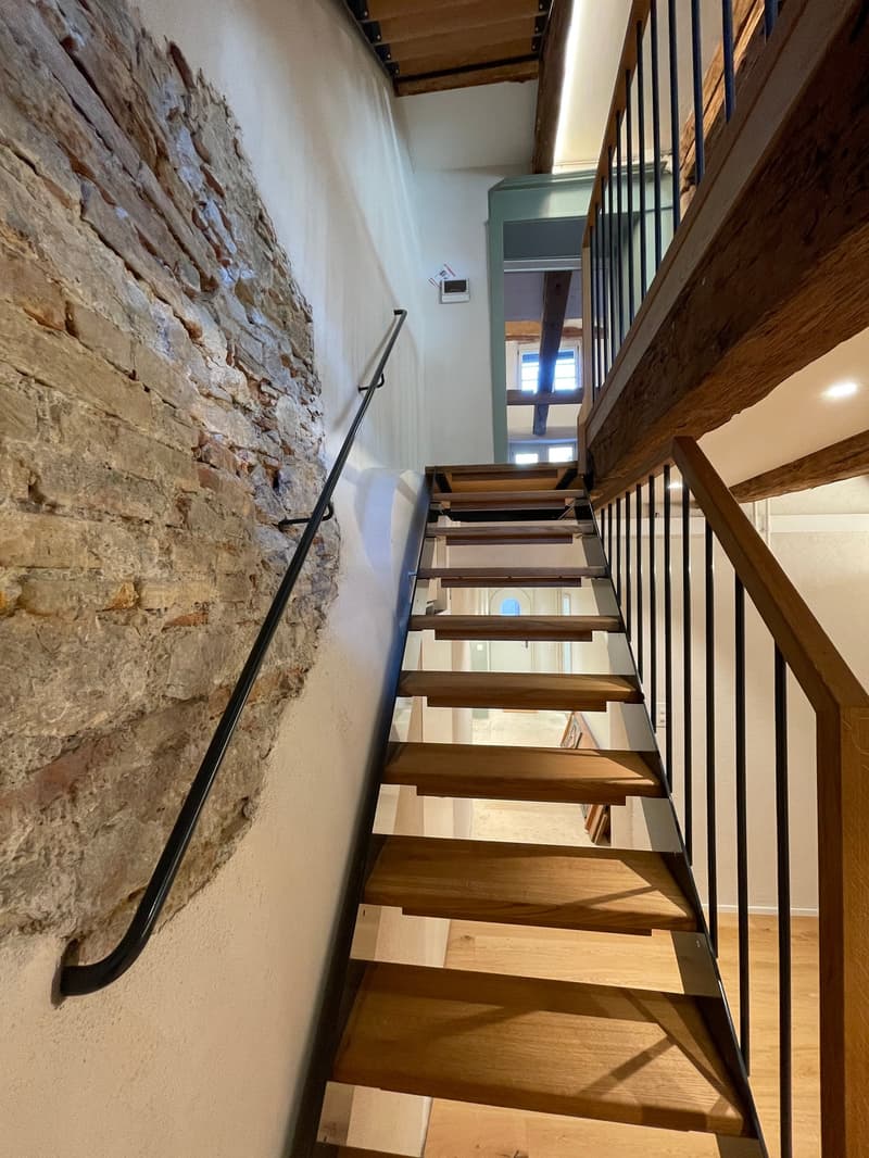 Treppe ins Obergeschoss mit Natursteinwand