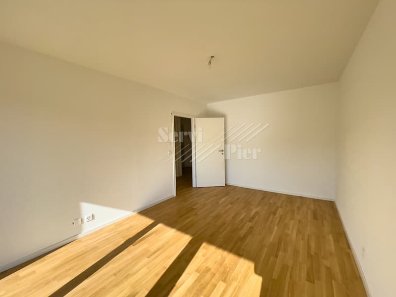 Empty room with white walls, hardwood flooring, and a single white door