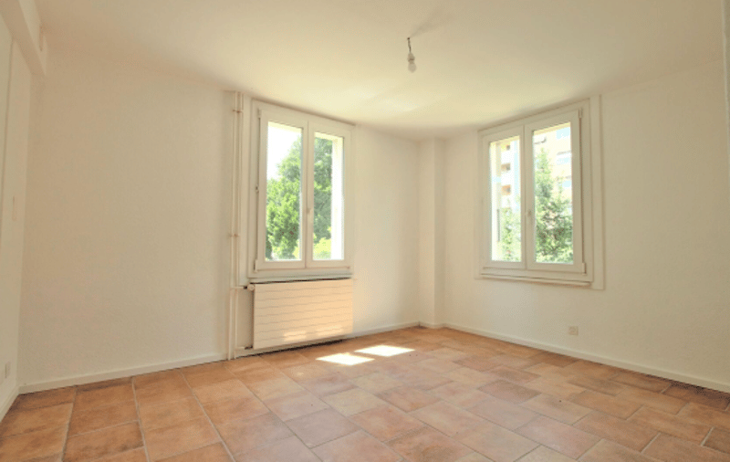 empty room, white walls, brown tiles, two windows, radiator