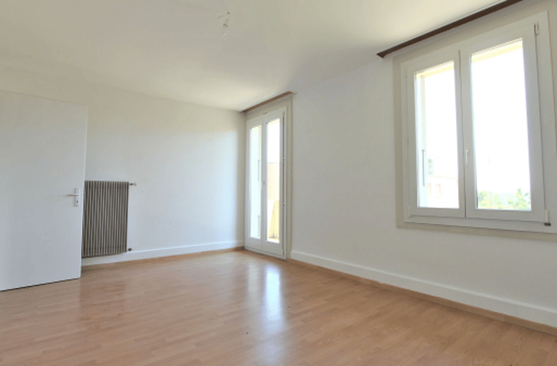 Empty room with hardwood floors, sliding doors, radiator, and windows