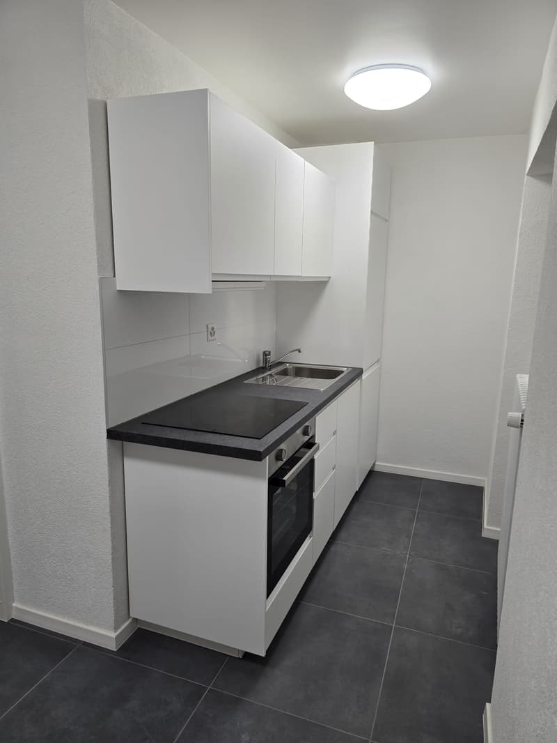Kitchen area with white cabinets, a black countertop, a modern sink with faucet, an electric stove, and a tiled floor