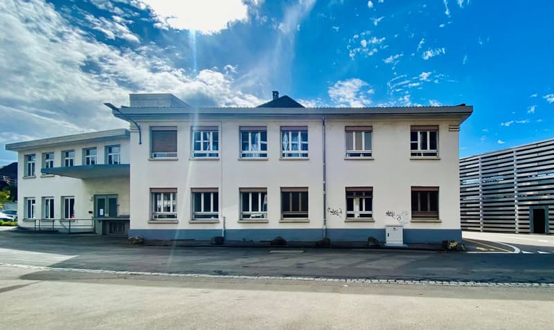 2 story white building, multiple windows, concrete floor