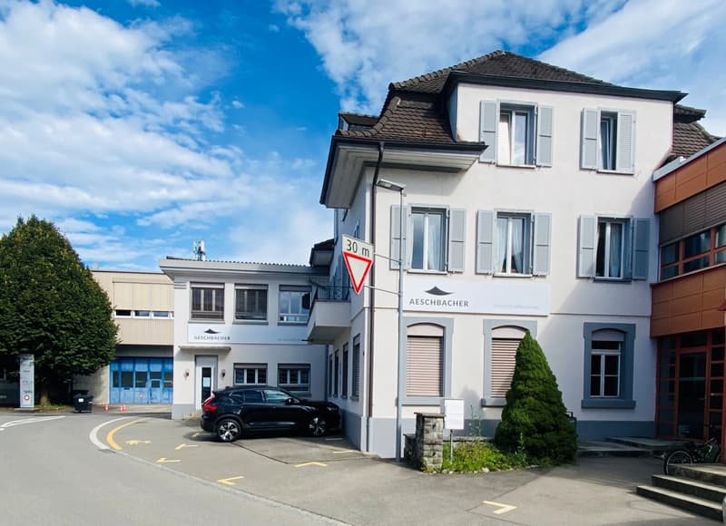 Modern two-story building, white walls, several windows, black car parked in front, sign indicating 30 m