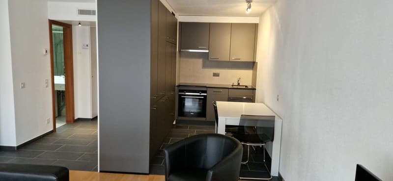 kitchen with built-in oven and sink, countertop, two stools, open space to dining area, leather chair, tiled floor
