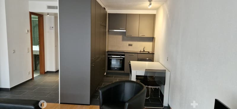 kitchen with built-in oven and sink, countertop, two stools, open space to dining area, leather chair, tiled floor