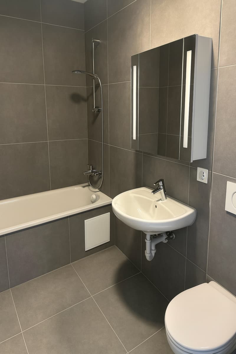white tiles, white bathtub, white sink, gray walls, mirror, power outlet, white toilet